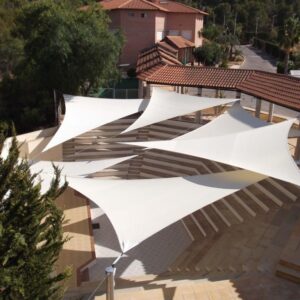 Toldos vela de HDPE instalados en patio exterior para protección solar y sombra arquitectónica - Rubber & Grass Chile.
